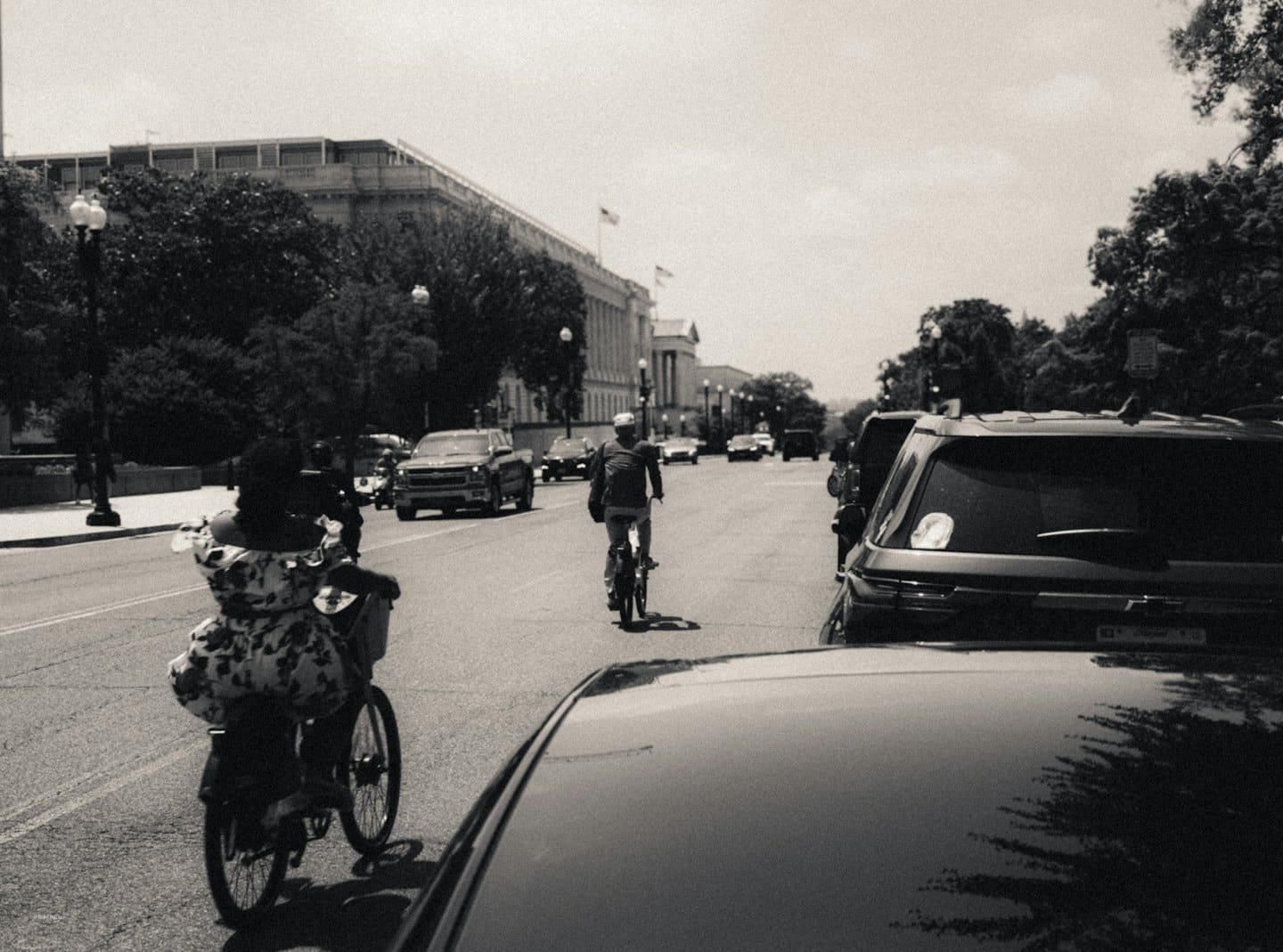 Due persone vanno in bicicletta per una strada di città.