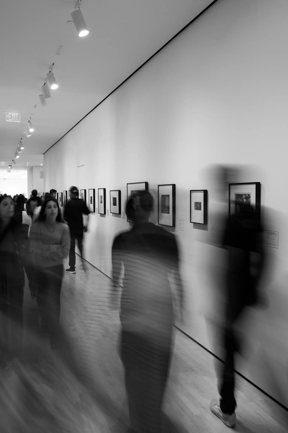 Persone che passeggiano in una galleria d'arte con opere d'arte alle pareti.