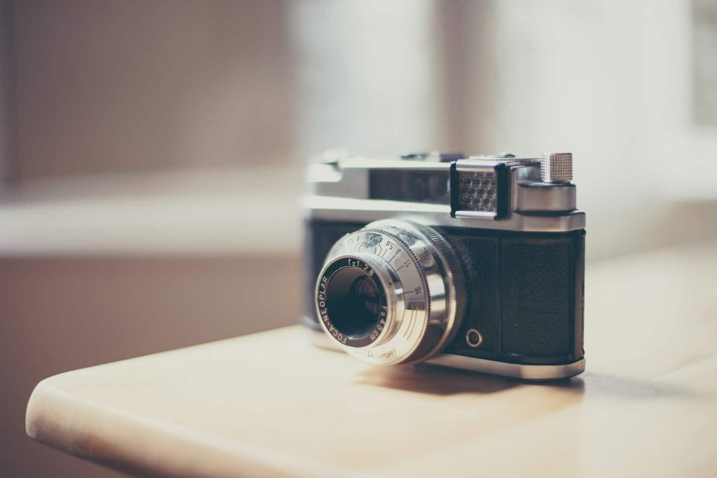 Macchina fotografica a pellicola vintage appoggiata su un tavolo di legno.
