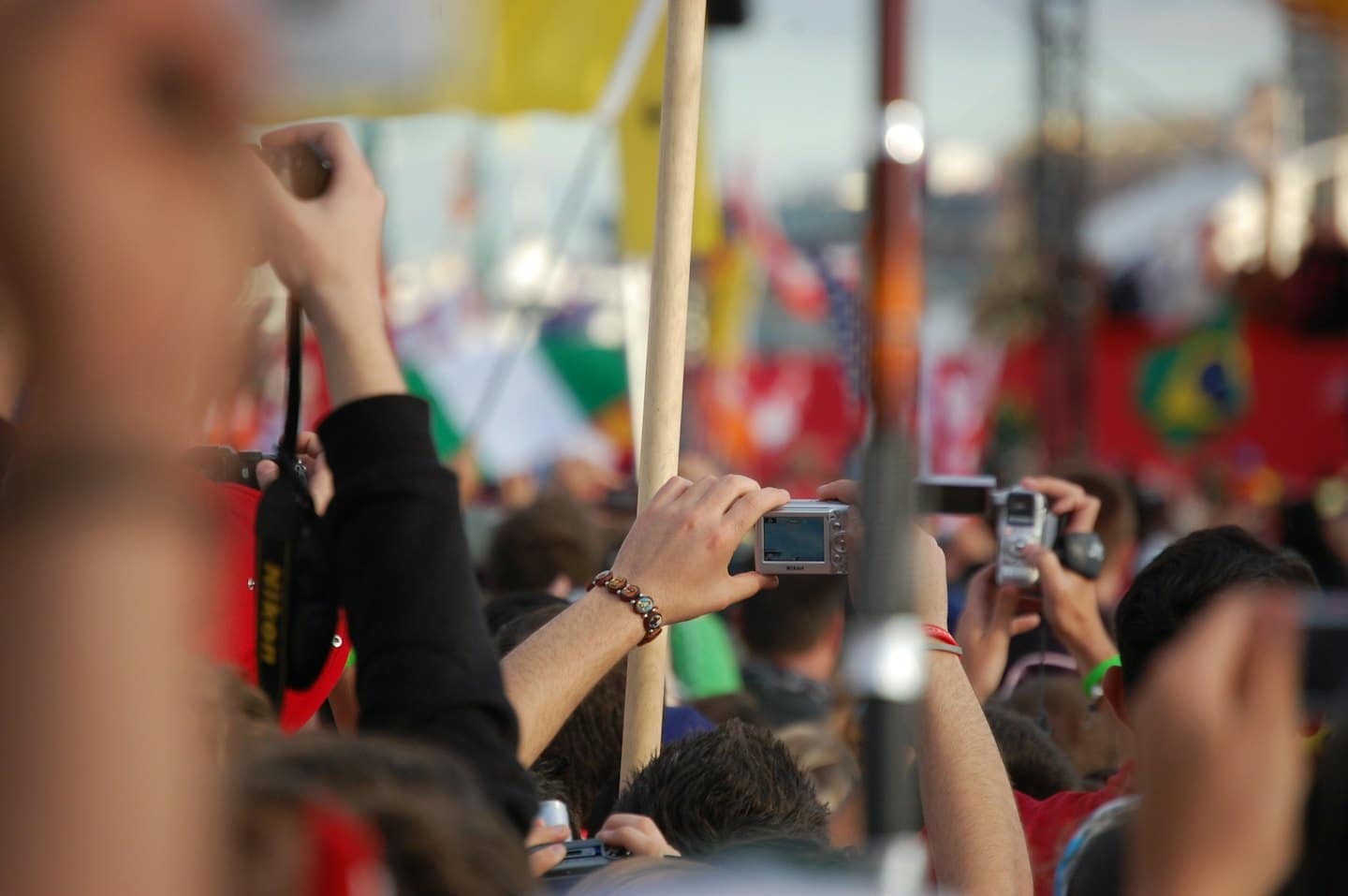 Membri della folla che tengono macchine fotografiche a un evento pubblico all'aperto.